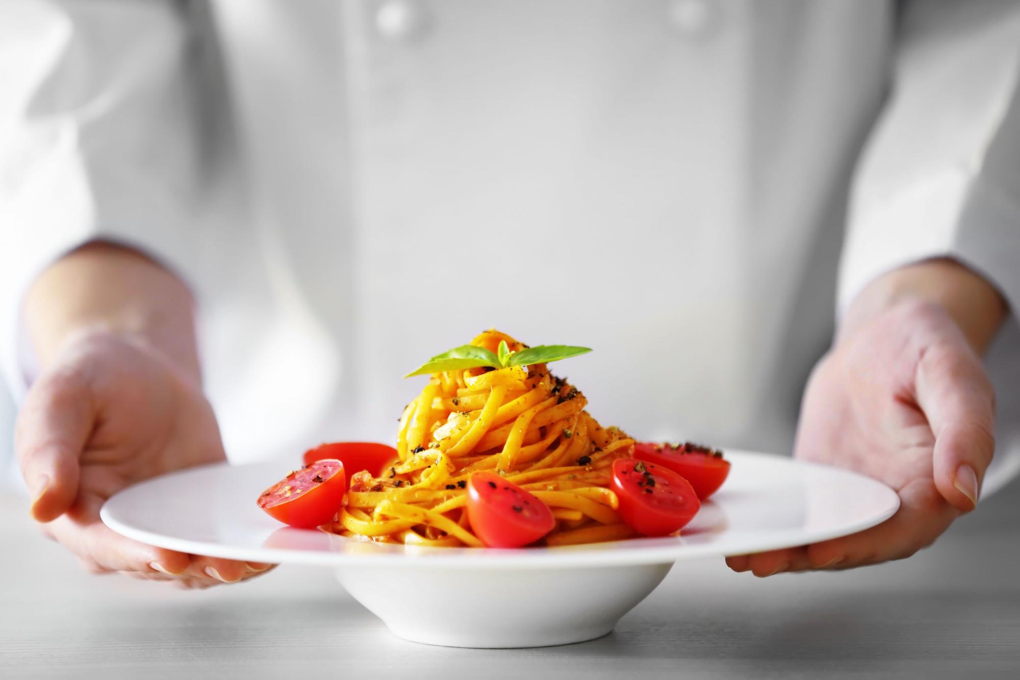 Chef locale che impiatta una porzione di pasta